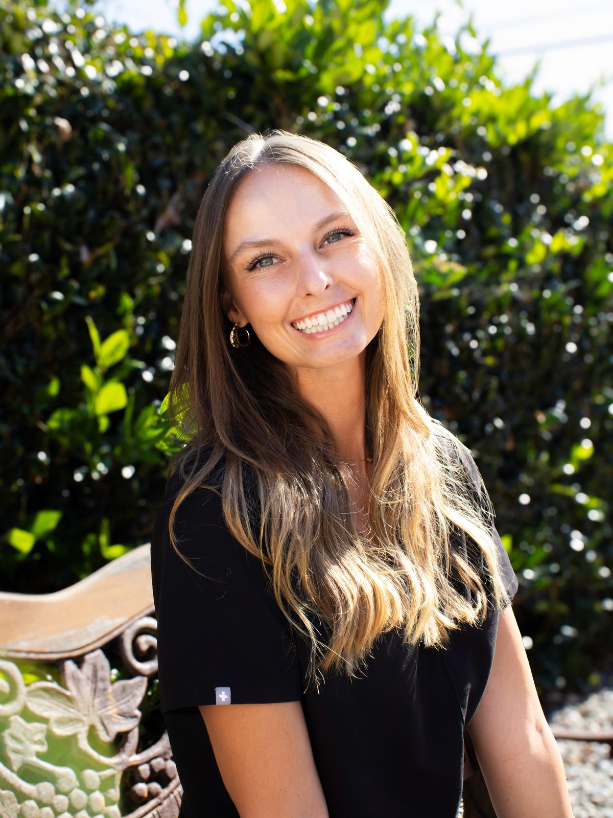 Dr. Hailey Cohon smiling outdoors in front of green hedges